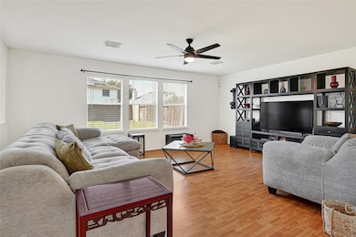 Bright and spacious living room. The room has wood flooring and ample natural light from the large windows overlooking the backyard.