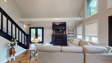 Living area with a fireplace, stairway, high vault
