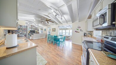 Kitchen featuring ceiling fan, vaulted ceiling with beams, track lighting, stainless steel appliances, and light wood-type flooring