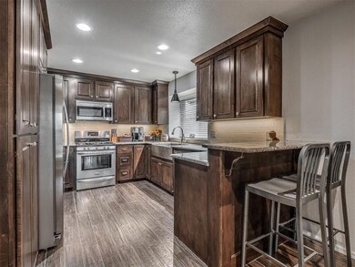 Kitchen featuring stainless steel appliances, a peninsula, dark brown cabinetry, a kitchen bar, and recessed lighting