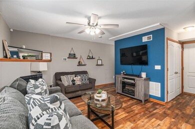 Living room featuring ceiling fan, dark wood-type flooring, and a fireplace