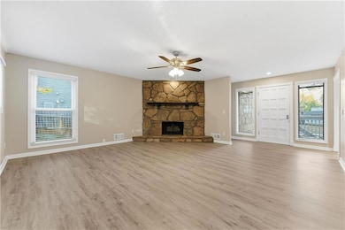 Unfurnished living room featuring light wood finished floors, a ceiling fan, and a fireplace