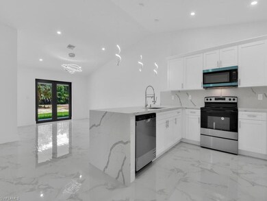 Kitchen featuring appliances with stainless steel finishes, a sink, recessed lighting, light marble finish flooring, and white cabinetry