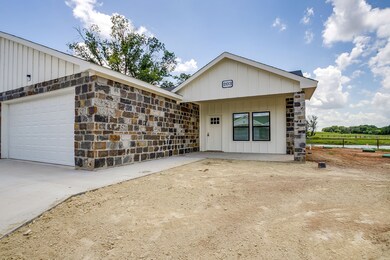 View of front of property with board and batten siding, stone siding, a garage, and concrete driveway