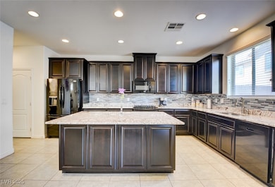 Kitchen with a sink, visible vents, black applianc