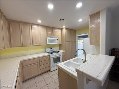 Kitchen with white appliances, tile countertops, l