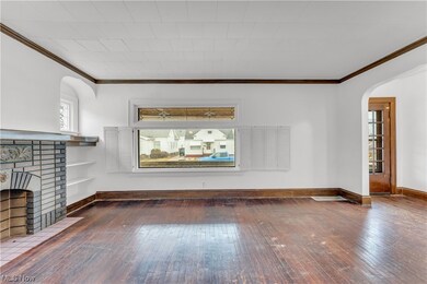 Unfurnished living room featuring a brick fireplace, dark hardwood / wood-style flooring, and crown molding