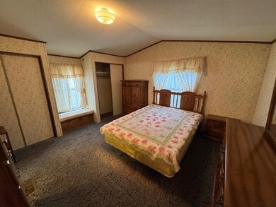 Bedroom with vaulted ceiling, ornamental molding, wallpapered walls, two closets, and dark carpet