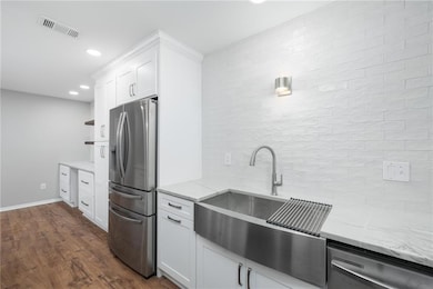 Kitchen featuring appliances with stainless steel finishes, dark wood-type flooring, white cabinetry, light stone countertops, and open shelves