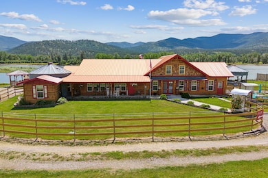 View of front of property featuring a rural view, a front yard, and Clarkfork River and mountain view