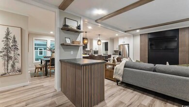 Kitchen featuring stainless steel fridge with ice dispenser, light wood-type flooring, beamed ceiling, white cabinets, and dark countertops