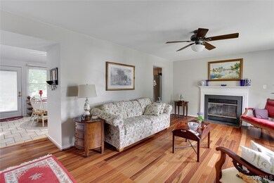 Living area featuring a ceiling fan, a fireplace with flush hearth, and light wood-type flooring