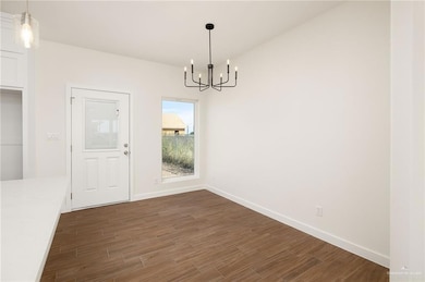 Unfurnished dining area with dark wood finished floors and a chandelier