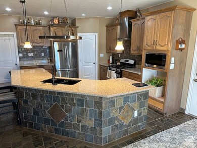 Kitchen featuring hanging light fixtures, a center island with sink, sink, and appliances with stainless steel finishes