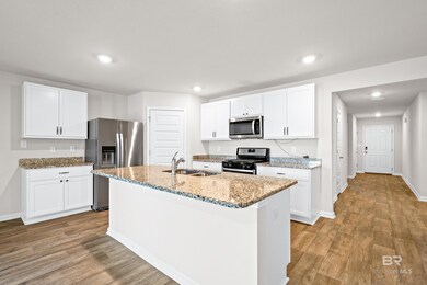 Kitchen featuring light hardwood / wood-style flooring, a center island with sink, light stone counters, white cabinets, and appliances with stainless steel finishes