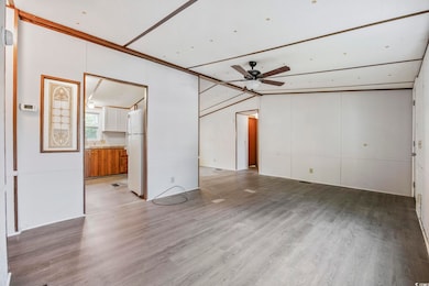 Unfurnished living room featuring ceiling fan, wood finished floors, and vaulted ceiling