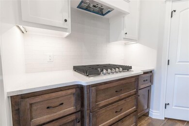 Kitchen with stainless steel gas cooktop, white ca