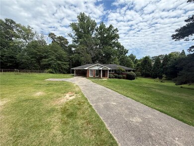 View of front facade featuring driveway, an attached carport, and a forest view