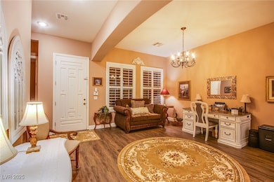 Living room featuring dark wood-style flooring, a desk, and a chandelier