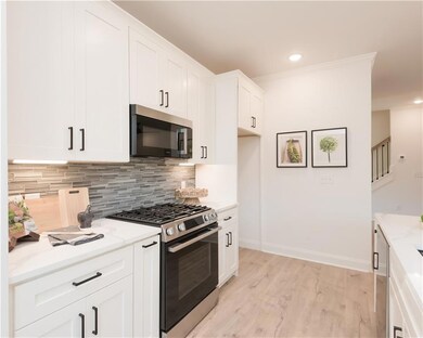 Kitchen with appliances with stainless steel finishes, white cabinetry, light wood finished floors, backsplash, and recessed lighting