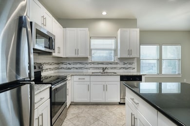Kitchen with appliances with stainless steel finishes, white cabinets, dark stone countertops, and recessed lighting