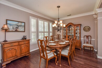 Formal dining with crown molding, plantation shutters, wood flooring and upgraded fixtures.