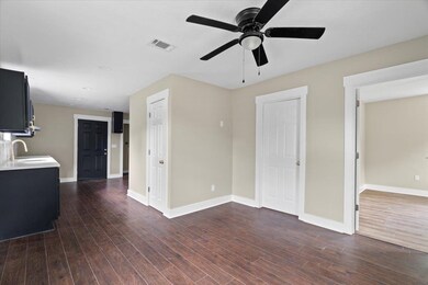 Living area featuring a ceiling fan, dark wood-style flooring, and baseboards