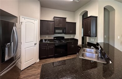 Kitchen with dark stone countertops, black applian