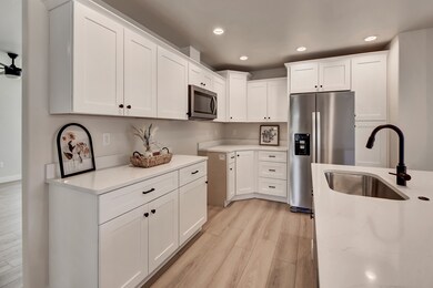 Kitchen featuring light wood finished floors, recessed lighting, appliances with stainless steel finishes, white cabinetry, and light stone countertops