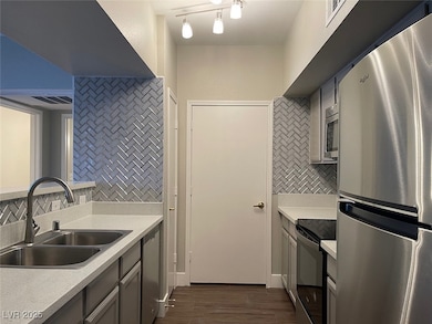Kitchen with stainless steel appliances, backsplash, dark wood finished floors, and gray cabinetry