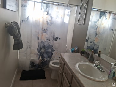 Full bath with toilet, curtained shower, tile patterned flooring, and vanity