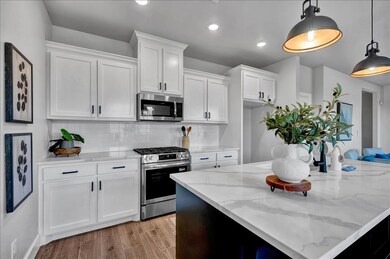 Kitchen with decorative backsplash, appliances with stainless steel finishes, white cabinetry, and recessed lighting