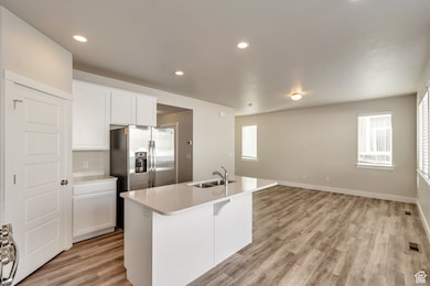 Kitchen with white cabinets, a kitchen island with sink, recessed lighting, light wood-style floors, and open floor plan