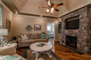 Beautiful stone fireplace and inlaid hardwood floors lend warmth and comfort to this spacious living room (Photo from previous listing with permission).