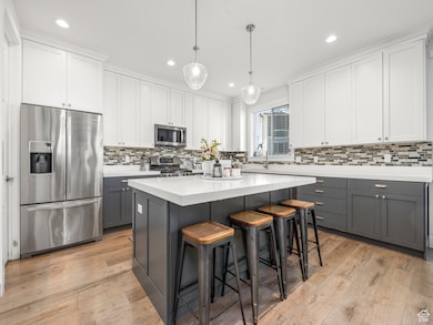 Kitchen featuring appliances with stainless steel finishes, light flooring / wood-style flooring, a center island, and gray cabinets
