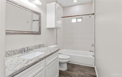 Bathroom with shower / bathing tub combination, vanity, toilet, baseboards, and wood finished floors
