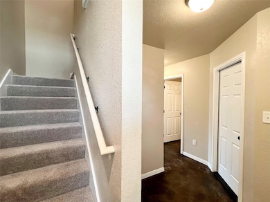 Staircase featuring finished concrete floors, a textured wall, and a textured ceiling