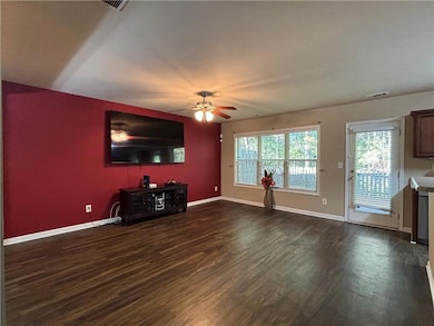 Unfurnished living room with dark wood-type flooring and a ceiling fan