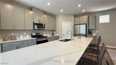 Kitchen with stainless steel appliances, gray cabinets, a kitchen breakfast bar, light stone countertops, and wood finished floors