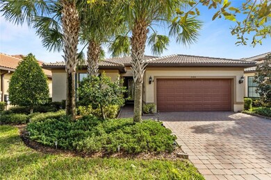 View of front facade with stucco siding, decorative driveway, a tiled roof, and a garage