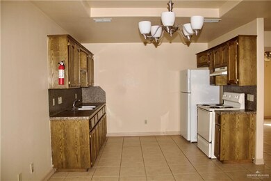 Kitchen with white electric range oven, visible vents, under cabinet range hood, a sink, and a notable chandelier