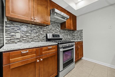 Kitchen featuring light stone counters, light til