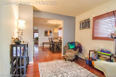 Living area with dark wood-style floors, arched walkways, and a wall unit AC