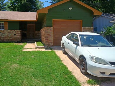 View of front facade featuring an attached garage, a front yard, driveway, and brick siding