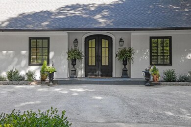 View of exterior entry with roof with shingles, french doors, stucco siding, and a porch
