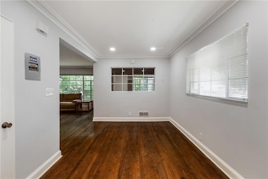 Empty room with dark wood-style floors, crown molding, and recessed lighting