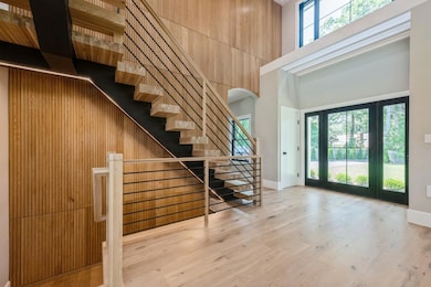 Entryway with a high ceiling, arched walkways, wood finished floors, and stairs