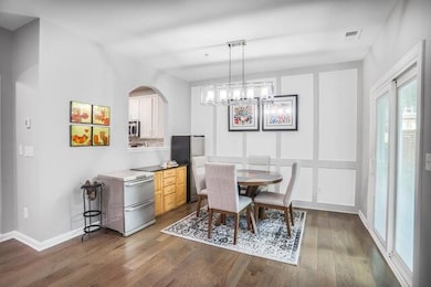 Dining space featuring dark wood finished floors, baseboards, a chandelier, and arched walkways