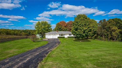 View of front facade featuring an outdoor structure, a garage, a rural view, and a front lawn