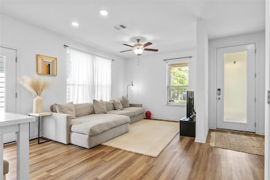 Living room featuring a ceiling fan, light wood-t